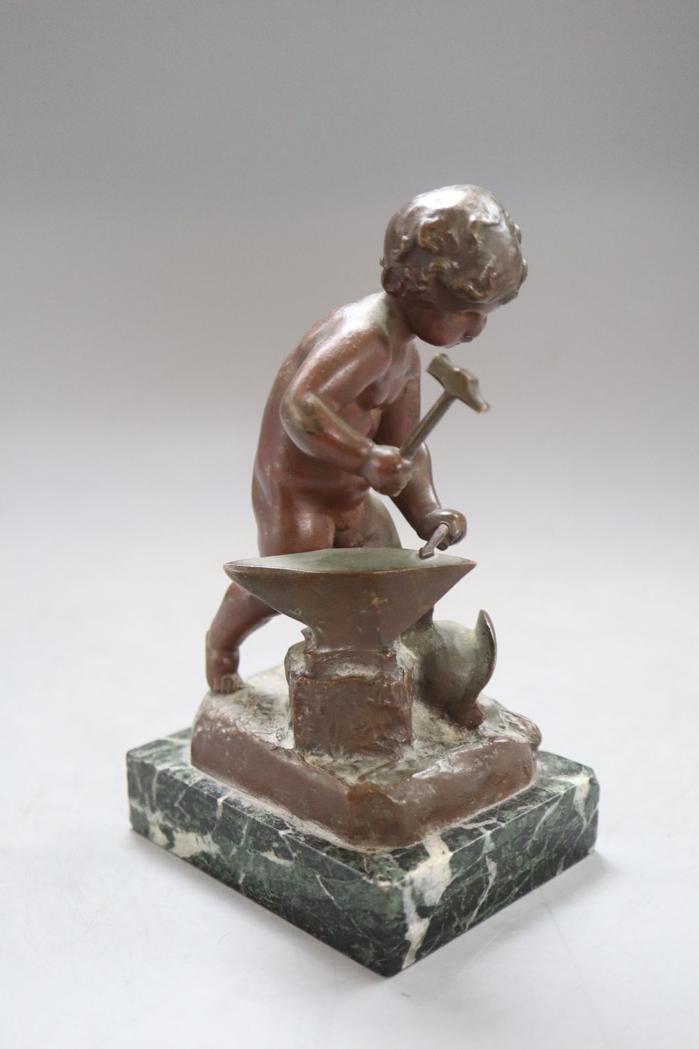 A bronze putto blacksmith, signed H. Capy, on marble base, height 15cm